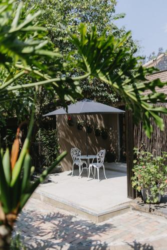 a table and two chairs under an umbrella at Meraki Country Manor in Lanseria