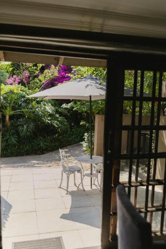 a patio with two chairs and an umbrella at Meraki Country Manor in Lanseria