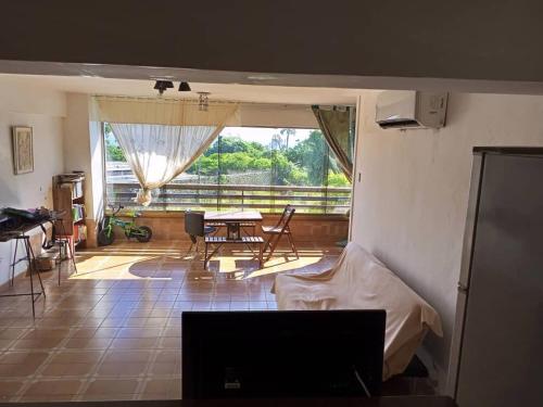 a living room with a bed and a table and a window at Apartamento frente al mar en Tanaguarenas in Caraballeda