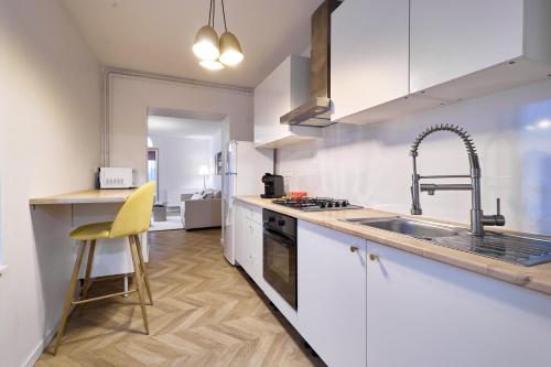 une cuisine avec des armoires blanches et un évier dans l'établissement Magnifique Appartement dans le Centre-Ville de Reims, Proche de la Gare et des Commodités, à Reims