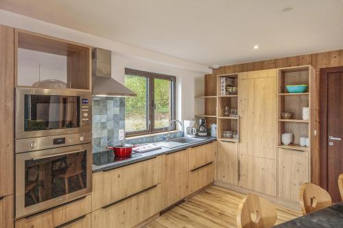 une cuisine avec des armoires en bois, un évier et une cuisinière dans l'établissement Hellébore, à Morillon