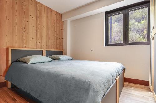 une chambre avec un lit dans une pièce aux murs en bois dans l'établissement Hellébore, à Morillon