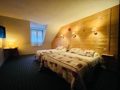 a bedroom with two beds and a wooden wall at Hotel le Sacca, nouvelle équipe in Cauterets