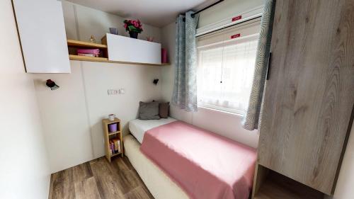 波讷地区圣朱利安Chez Bruno & Sophie Mobil home luxe 6-8P BORA BORA的一间小卧室,配有粉红色的床和窗户