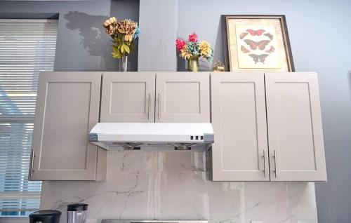 a kitchen with white cabinets and flowers on the wall at Garden Hideaway Minutes to Fishtown in Philadelphia