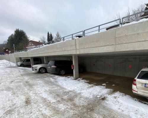 a parking lot with cars parked under an overpass at SKI apartment - Rezidence LYSÁ HORA in Rokytnice nad Jizerou