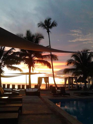 a sunset at a resort with palm trees and a pool at Cadaques Caribe Pez 103 in Bayahibe