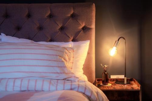 een slaapkamer met een bed en een lamp op een nachtkastje bij Skylark House Padstow Stylish Victorian Townhouse with Private Sauna in Padstow