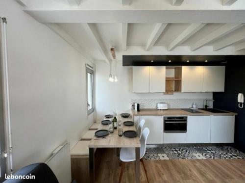 une cuisine avec des armoires blanches et une table avec des chaises dans l'établissement Élégant duplex neuf à 30 m de l'Océan avec parking, à Lacanau