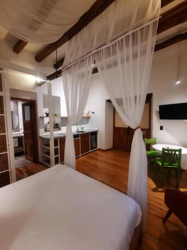 a bedroom with a bed with curtains and a kitchen at Hostal Suite Le Fabrique in Cuenca