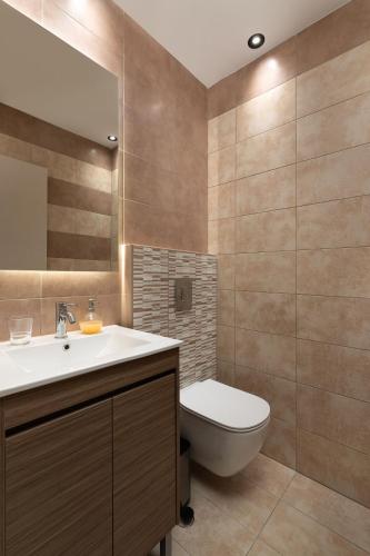 a bathroom with a toilet and a sink and a mirror at Rhodes SkyLine Suite with out Door Jacuzzi Sea View A1 in Ixia
