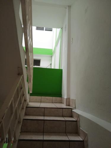 a staircase in a building with a green wall at Hotel Green Monkey in Flores