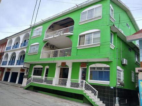 a green building with white windows and balconies at Hotel Green Monkey in Flores