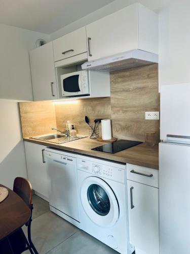 une cuisine avec un lave-linge et un micro-ondes dans l'établissement Joli appartement lumineux et calme, à Sérignan