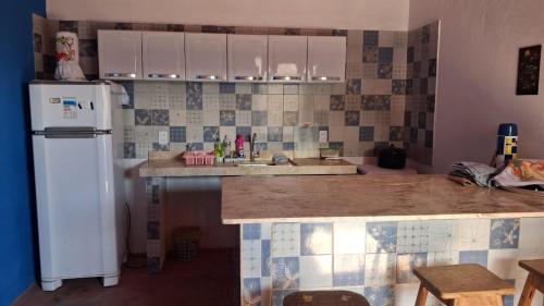 a kitchen with a white refrigerator and a sink at Chalé marlin azul in Icapuí