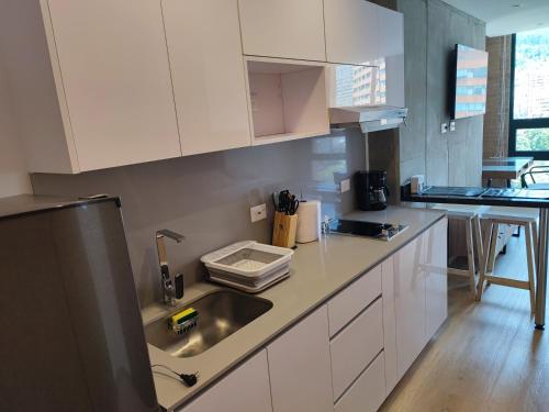 a kitchen with white cabinets and a stainless steel sink at ApartaSuite Centro Internacional in Bogotá