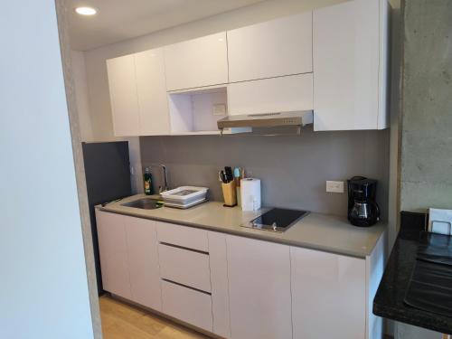 a kitchen with white cabinets and a counter top at ApartaSuite Centro Internacional in Bogotá