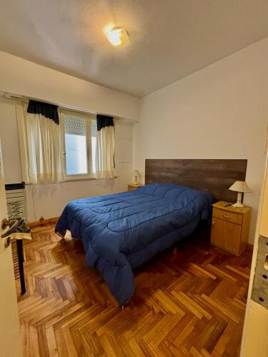 una camera da letto con un letto grande con una coperta blu di Departamento de dos ambientes en plaza Colon a Mar del Plata