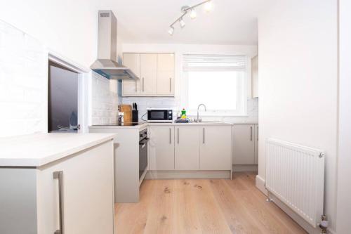 a white kitchen with white cabinets and a sink at Coastal Charm 1br Flat Near The Sea Street Parking in Hollington