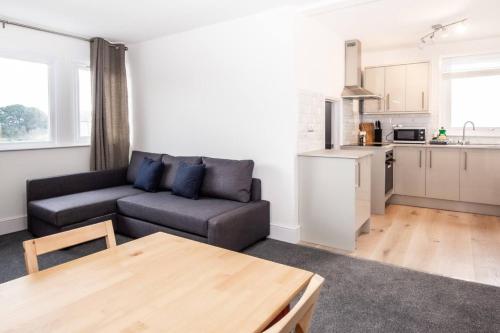 a living room with a couch and a kitchen at Coastal Charm 1br Flat Near The Sea Street Parking in Hollington