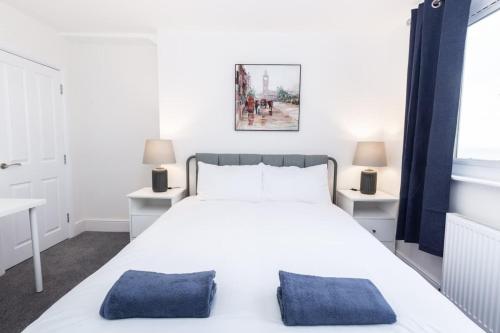 a bedroom with a white bed with blue pillows at Coastal Charm 1br Flat Near The Sea Street Parking in Hollington