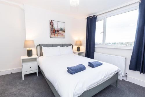 a bedroom with a bed with two blue towels on it at Coastal Charm 1br Flat Near The Sea Street Parking in Hollington