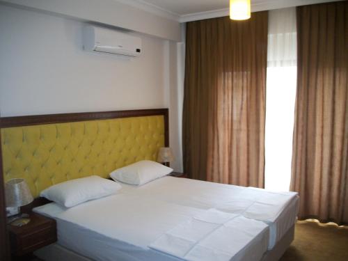 a bedroom with a large white bed with a yellow headboard at Siesta Apart Otel İzmir in İzmir