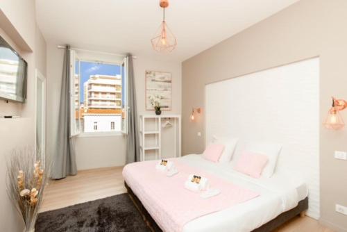 une chambre avec un lit blanc et une grande fenêtre dans l'établissement Lecerf Croisette, à Cannes