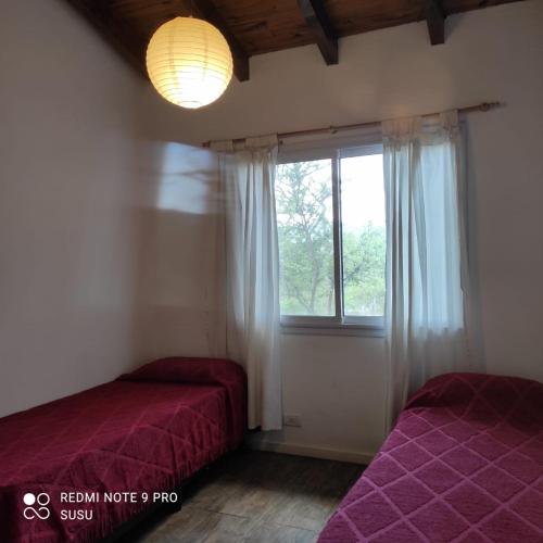 ein Schlafzimmer mit zwei Betten und einem Fenster in der Unterkunft Casa El ALto 1 in Villa General Belgrano