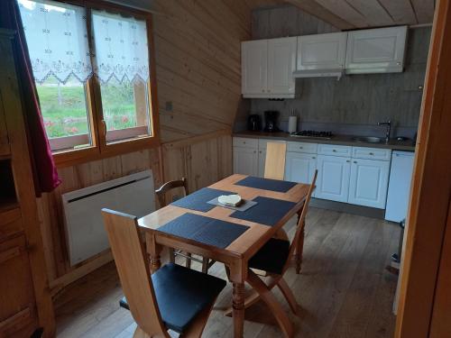 une cuisine avec une table et des chaises dans une cabine dans l'établissement CHALET DU PERE NOEL 10 minutes from Gérardmer, à Ban-sur-Meurthe-Clefcy