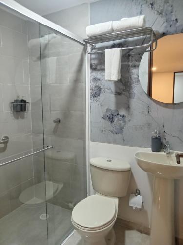 a bathroom with a toilet and a shower and a sink at Buendía Hotel in Barrancabermeja