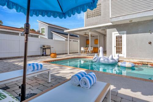 a house with a swimming pool with an umbrella at 5BR Villa with Heated Pool & BBQ - SoHo, Downtown Tampa and Airport in Tampa
