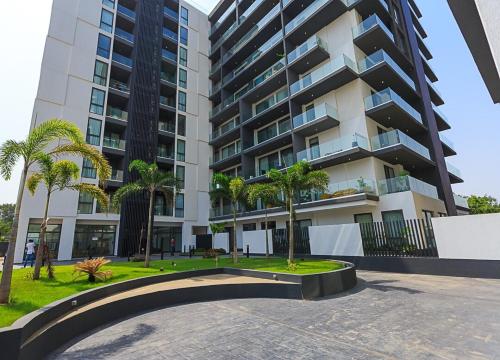 a large apartment building with palm trees in front of it at luxury 1 br 7 mins from Airport, with Gym & Pool in Mamobi