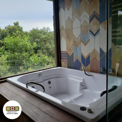 a bath tub in a bathroom with a window at Casas da Paty in Santana do Riacho