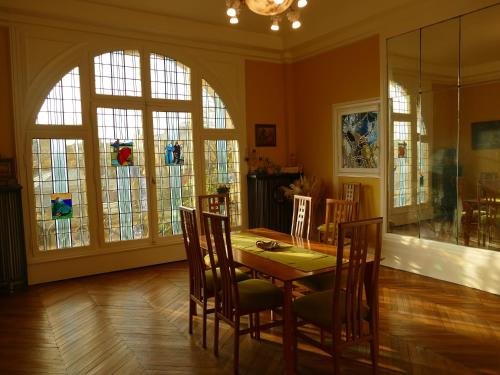 une salle à manger avec une table, des chaises et des vitraux dans l'établissement Villa Arcadia, à Chauny