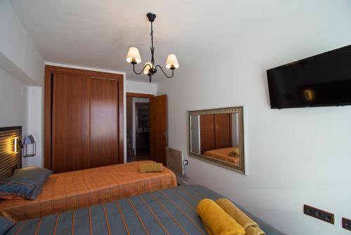 a bedroom with two beds and a flat screen tv at SnowGranada Hight Level Galatino in Sierra Nevada