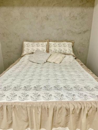 a bed with a white comforter and pillows on it at Aconchegante casa em Marataizes in Marataizes