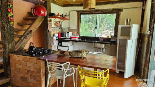 a kitchen with a counter and yellow chairs in it at Casas da Paty in Santana do Riacho