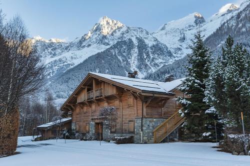 une cabane en rondins dans les montagnes avec de la neige sur le toit dans l'établissement Cottage des Houches - Happy Rentals, aux Houches
