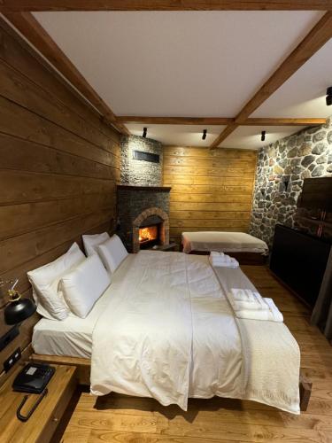 a bedroom with a large bed and a fireplace at Hotel Ambassador Voskopojë in Voskopojë