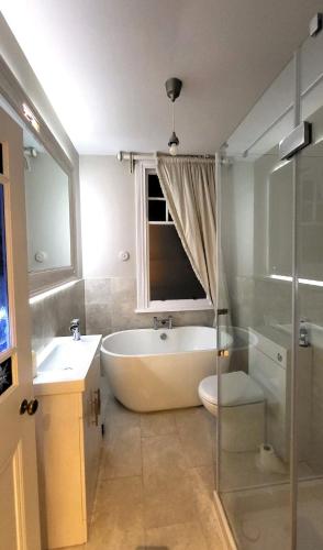a bathroom with a tub and a toilet and a sink at St Michaels Town House - Elegant and Large Holiday Home in the Heart of Gloucester in Gloucester