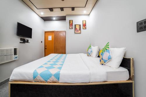 a bedroom with a bed with a tv on the wall at Hotel O Home Gautam Homestay in Dehradun