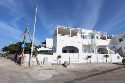 a white building with palm trees in front of it at Mediterranea in Marina di Pescoluse