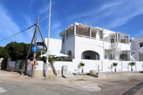 a white building with palm trees in front of it at Mediterranea in Marina di Pescoluse