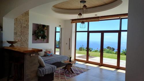 a living room with a couch and a large window at Villa - Cantinho do Paraíso in Santo Espírito
