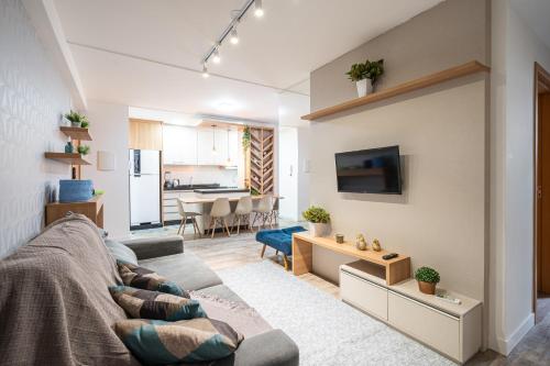 ein Wohnzimmer mit Couch und Küche in der Unterkunft Aptos completo com vista mar pé na areia em Barra Velha em condomínio Resort com Spa, Piscina, quadra de futebol, Sala de jogos, brinquedoteca, Complexo com diversos comércios in Barra Velha