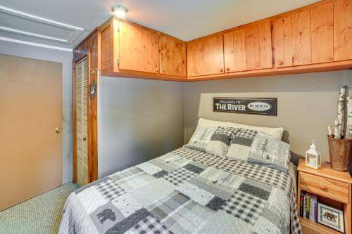 a bedroom with a bed and wooden cabinets at Fish, Hike and Relax Riverfront Manistique Cabin in Manistique