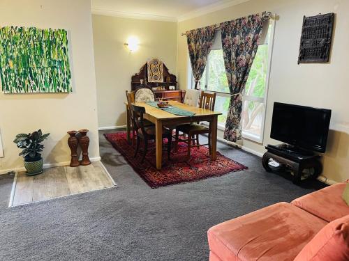 a living room with a table and a tv at Red Steps - 4 bedroom home in Narrandera