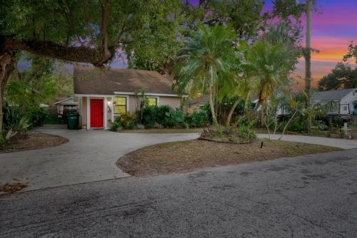 a house with a red door and a driveway at Zen Jungle House by Busch Gardens Sleeps 12 with Outdoor Games & Detached Play Space! in Tampa