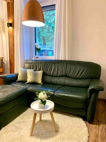 a green leather couch in a living room with a table at FeWo im Chalet Style mit Kamin und Wärmekabine in Geyer